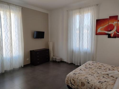 a bedroom with a bed and curtains and a tv at B&B Intero Appartamento Forum e Metro Milanofiori in Assago