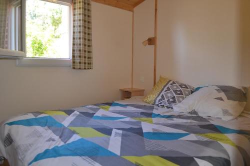 Un dormitorio con una cama con un edredón colorido y una ventana en Chalet grand confort, en Beynat