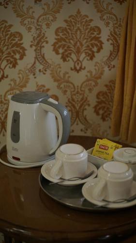 a tea pot and saucers on a table at Le Desa Resort Syariah in Wonosobo