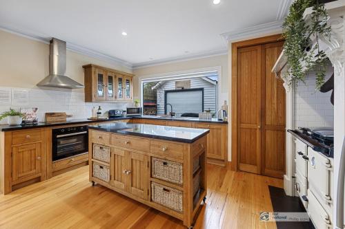 a kitchen with wooden cabinets and a large island at Federation House on Genesta St Central Cowes in Cowes