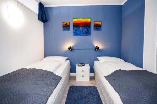 - 2 lits dans une chambre aux murs bleus dans l'établissement Wohlfühloase mit Meerblick, à Sierksdorf