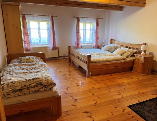 two beds in a room with wooden floors and windows at Chalupa Chřiby in Deštné v Orlických horách