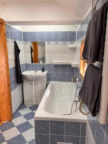 a blue tiled bathroom with a tub and a sink at Chalupa Chřiby in Deštné v Orlických horách