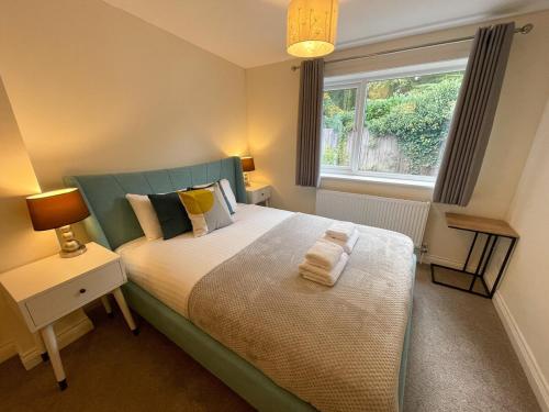 een slaapkamer met een bed met een groen hoofdeinde en een raam bij Stunning House In Beautiful Madingley Village 
