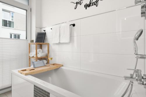 une salle de bains blanche avec une baignoire et un ordinateur portable sur une étagère. dans l'établissement Golden-Loft 92qm, zentral & ruhig, Messe I HBF nah, à Essen