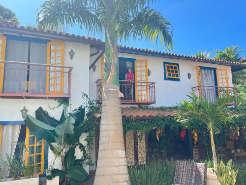 a woman standing on the balcony of a house with a palm tree at Villa Lulu Geribá in Búzios