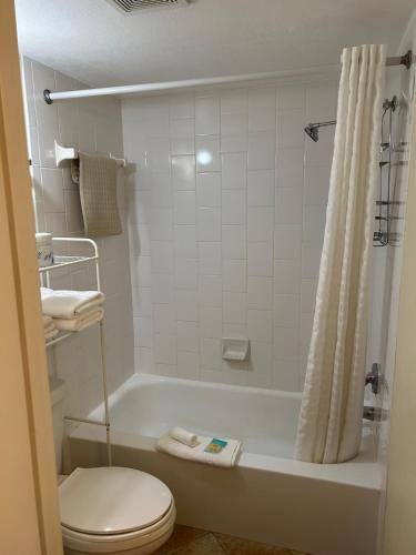 a bathroom with a toilet and a tub with a shower at Oceanside Inn in Daytona Beach