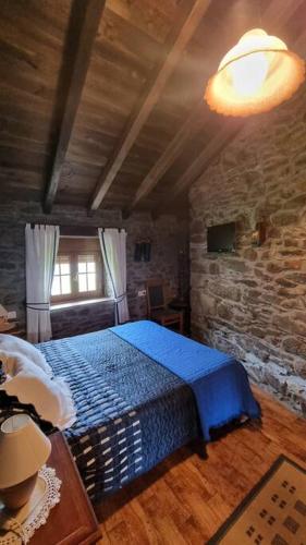 a bedroom with a blue bed and a stone wall at Casa Rural Maria de Isidro in Caboalles de Arriba