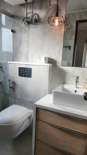 ein Badezimmer mit einem Waschbecken, einem WC und einem Spiegel in der Unterkunft Uber Chic Boutique Stay In City Center in Jaipur