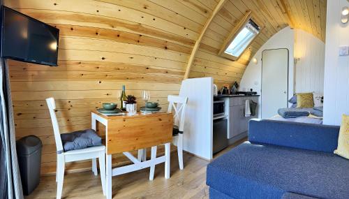 a living room with a table and a room with a kitchen at Malhamdale Glamping in Skipton