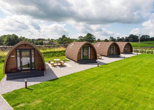 a row of three domes in a field with grass at Malhamdale Glamping in Skipton