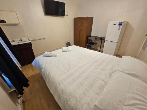 a bedroom with a white bed and a refrigerator at Bruce Rooms in London