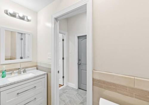 Baño blanco con lavabo y espejo en Newly Renovated Guest Rooms near Transportation, en Filadelfia