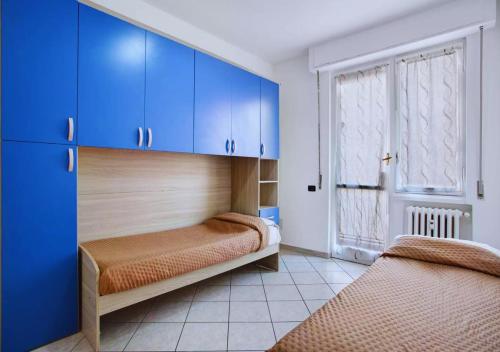 2 letti in una camera con armadi blu e finestra di Appartamento Tre Locali Accogliente A Nova Milanese ,Vicinanza A Milano e Stadio Monza a Nova Milanese