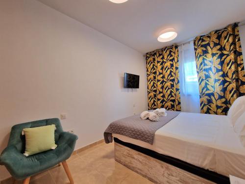 a bedroom with a bed and a green chair at Las Rocas by the Ocean, Wifi and Sea View in Los Abrigos