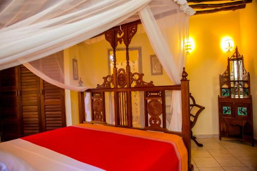 a bedroom with a canopy bed with red sheets at 3 Bed Villa Sleeps 6 - Pool Garden Chef Option in Diani Beach