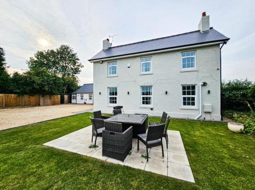 een wit huis met een tafel en stoelen in de tuin bij Granary Villa in Kidderminster