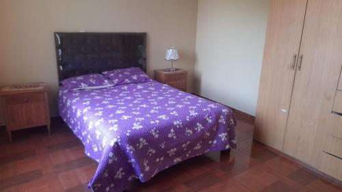 a bedroom with a purple bed with a purple comforter at DEPARTAMENTOS AMOBLADOS EN JOSE LUIS BUSTAMANTE Y RIVERO AREQUIPA -PERU in Arequipa