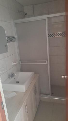 a white bathroom with a sink and a shower at DEPARTAMENTOS AMOBLADOS EN JOSE LUIS BUSTAMANTE Y RIVERO AREQUIPA -PERU in Arequipa