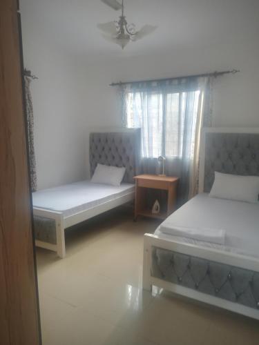 een kamer met 2 bedden, een tafel en een raam bij Vipingo royal homes in Kilifi