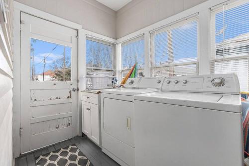 a white laundry room with a washing machine and windows at Festive Nest - Tranquil Escape Close to the Beach in Galveston