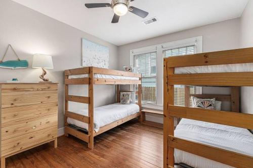 a bedroom with two bunk beds and a ceiling fan at Festive Nest - Tranquil Escape Close to the Beach in Galveston