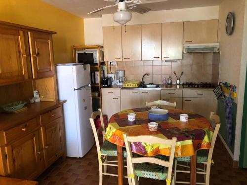 Il comprend une cuisine équipée d'une table avec des chaises et d'un réfrigérateur blanc. dans l'établissement Appartement T2, 4 Couchages, Terrasse, Jardinet, Parking, Proche Commerces et Plage, Le Barcarès - FR-1-81-298, au Barcarès