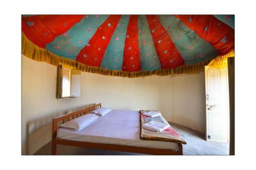 a bedroom with a bed with a parachute ceiling at Jaisalmer Safari Base & Camp in Khuri