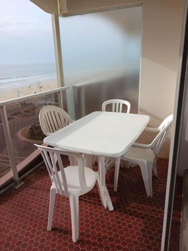 une table blanche et des chaises sur un balcon avec l'océan dans l'établissement saint jean de mont, Superbe studio balcon face mer, à Saint-Jean-de-Monts