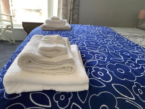 a pile of towels sitting on top of a bed at Cosy and Comfortable Newly Refurbished Family Home in Hull