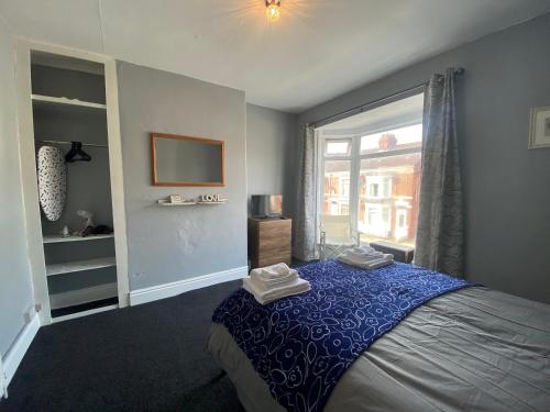 a bedroom with a bed with a blue blanket and a window at Cosy and Comfortable Newly Refurbished Family Home in Hull