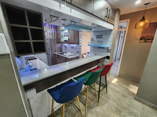 a kitchen with a bar with colorful bar stools at 1901 on Hightide in Amanzimtoti