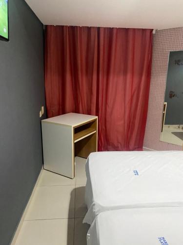 a bedroom with two beds and a red curtain at Marinas Flat 116 in Tambaú