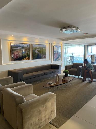 a person sitting on a couch in a living room at Marinas Flat 116 in Tambaú