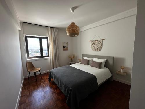 a bedroom with a bed and a chair and a window at Ponte Velha in Peniche