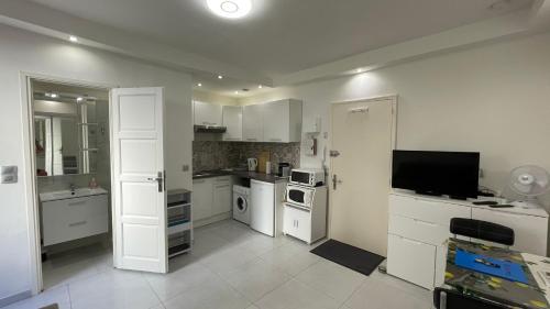 eine Küche mit weißen Schränken und einem Flachbild-TV in der Unterkunft Studio rue piétonne proche plage in Menton