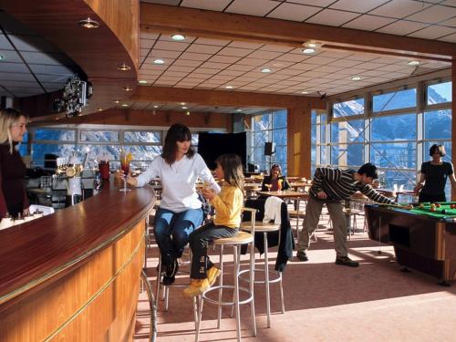une femme et un enfant assis dans un bar dans l'établissement Appartement T2 cabine pour 8 pers, ski aux pieds, bien équipé, proche commerces et sports - FR-1-262-137, à Forest des Baniols