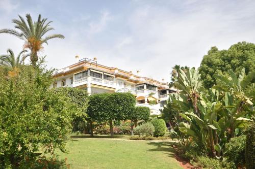 um grande edifício branco com árvores e arbustos em Apartman La Concha in Puerto Banus em Marbella