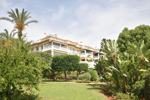 een groot wit gebouw met bomen en struiken bij Apartman La Concha in Puerto Banus in Marbella
