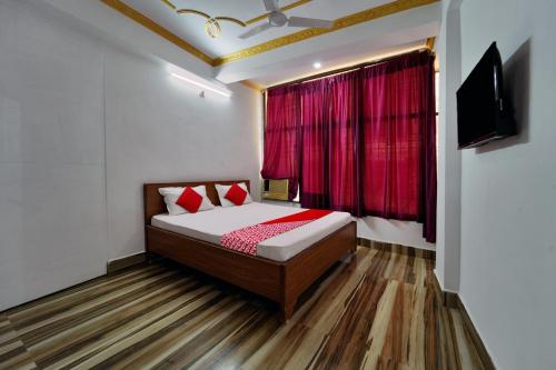 Un dormitorio con una cama y una ventana con cortinas rojas. en Super Hotel O Mahal Inn, en Patna