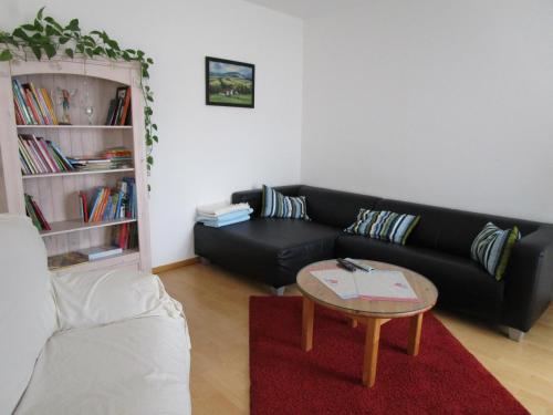 sala de estar con sofá negro y mesa en Location Chez Helmut, en Rorschwihr