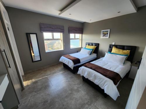 a bedroom with two beds and two windows at Durban Holiday Apartments , 1901 on High Tide in Amanzimtoti