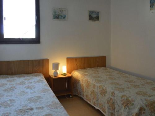 une chambre avec deux lits et une lampe sur une table de chevet dans l'établissement Appartement moderne avec terrasse à 1500m de la plage, parking privé, lave-linge, 4 couchages - FR-1-249-177, au Cap d'Agde