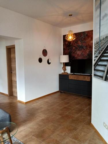 a living room with a staircase and a television at Ehem. Sächsisch-Bayrischer Hof in Pöhl