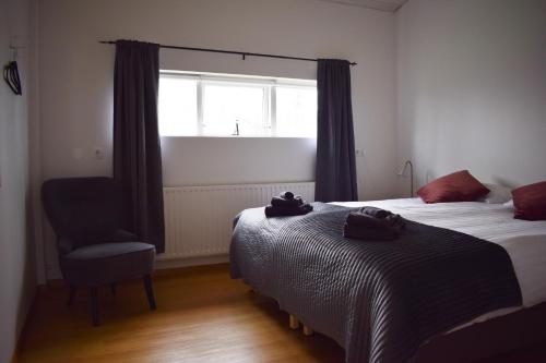 a bedroom with two beds and a chair and a window at The Organist House in Golden Circle in Skálholt