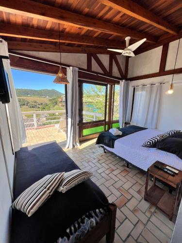 a bedroom with two beds and a large window at Pousada Sonho do Vale in Praia do Rosa
