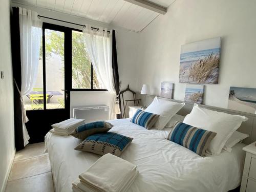 a large white bed in a room with a window at Maison de Charme à St Clément des baleines in Saint-Clément-des-Baleines