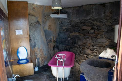 een badkamer met een roze bad en een stenen muur bij Unique House - Pool, Terrace & Amazing View in Ribeira Brava