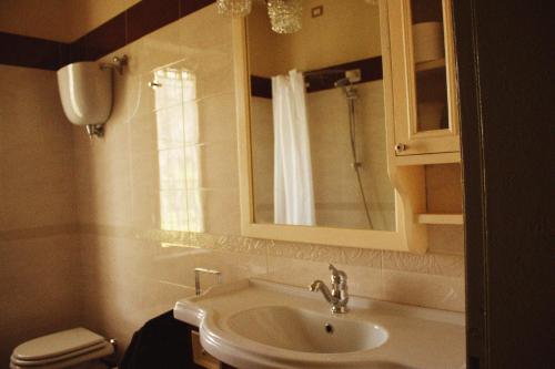 y baño con lavabo, espejo y aseo. en il nuvoloso, en Città della Pieve