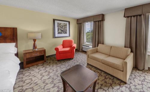 a hotel room with a bed and a couch and a chair at Hilton Garden Inn Tampa East Brandon in Tampa